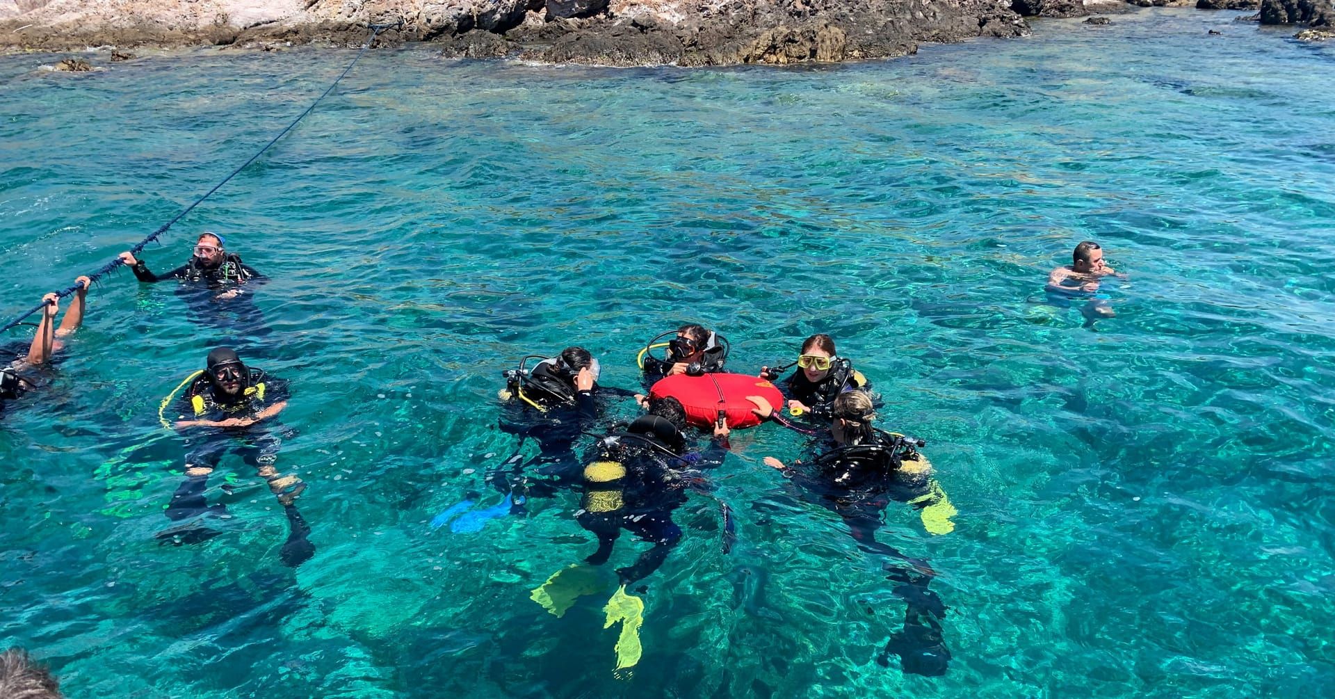 A group of divers at the surface with their instructor and a marker buoy