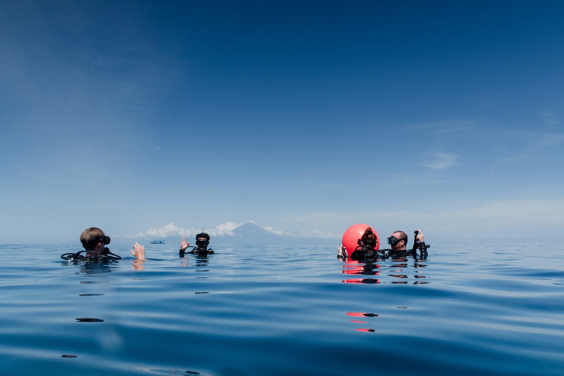 Divers at the surface with a volcano on the horizon